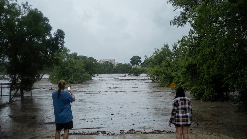 Mike Erulenfeld and Kala Martin watch as the Pedernales River floods near Old Kerr Highway on...