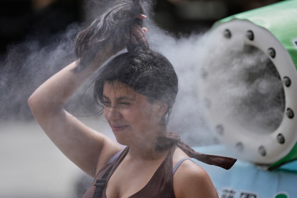 Una persona se refresca en una unidad de enfriamiento durante un caluroso día en el templo...