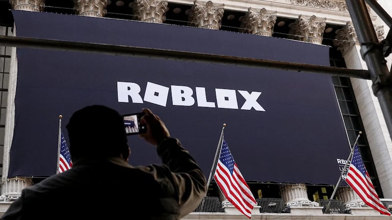 Un hombre fotografía una pancarta de Roblox colocada en la fachada de la Bolsa de Nueva York...