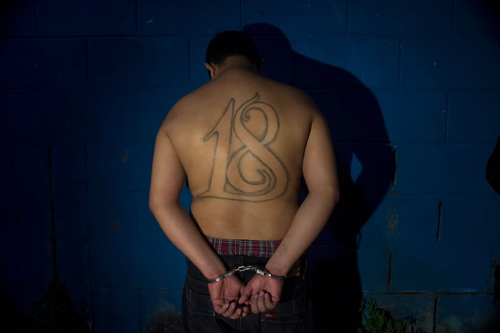FILE - A leader of the Barrio 18 gang stands handcuffed facing a wall after his arrest in San...