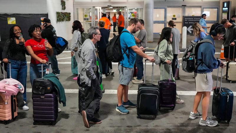 Airline passengers wait in long lines outside the terminal to get through the TSA security...