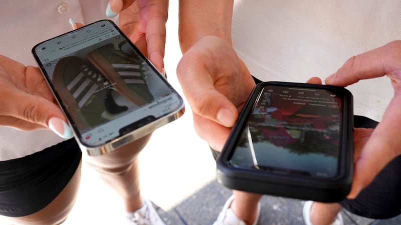 ARCHIVO - Dos jóvenes usan sus teléfonos para ver redes sociales, el 8 de noviembre de 2024,...