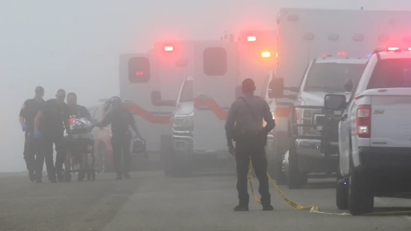 Emergency personnel rush a victim of a small plane crash to an awaiting ambulance near...