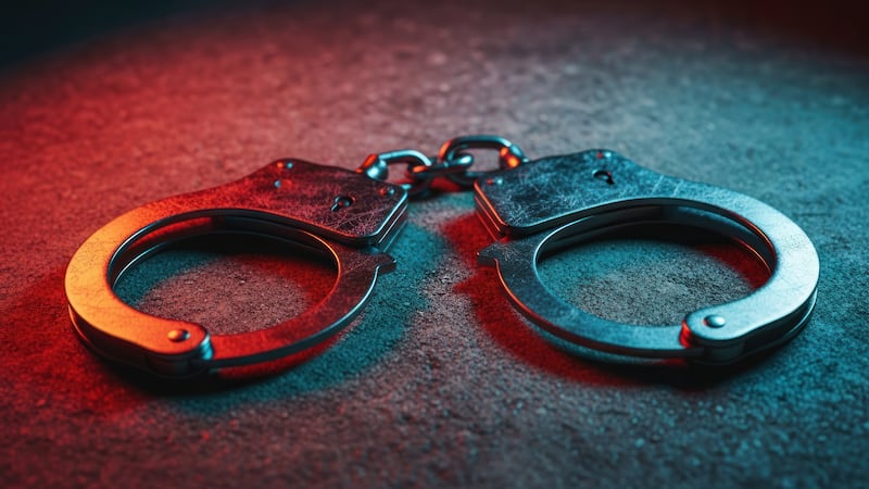 Metal handcuffs on a textured surface, bathed in red and blue light