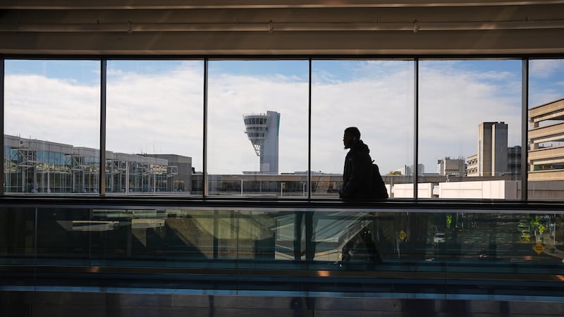 Un viajero camina frente a una torre de control en el Aeropuerto Internacional de Filadelfia...