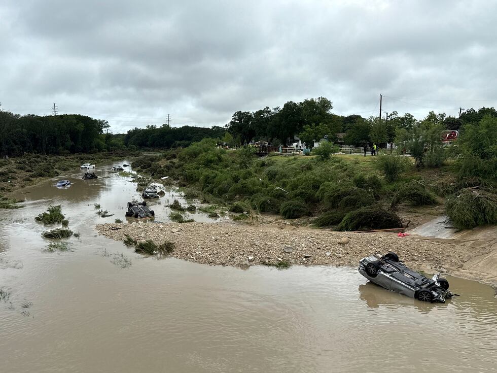 Varios vehículos yacen en el río tras ser arrastrados por inundaciones en San Antonio, Texas,...