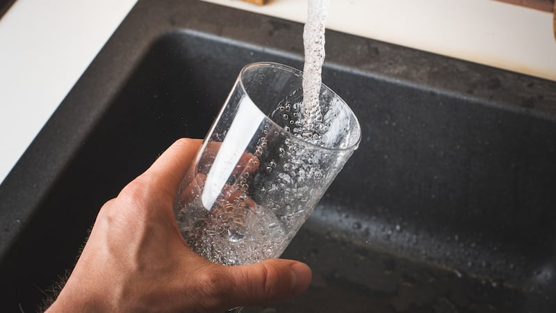 Filling glass of water from stainless steel kitchen faucet. Drinking water concept. Austria...
